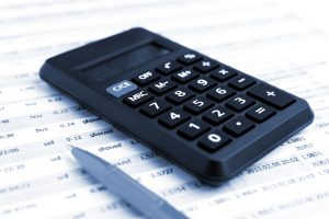 Nahaufnahme eines Taschenrechners und Stifts auf einem Finanzbericht