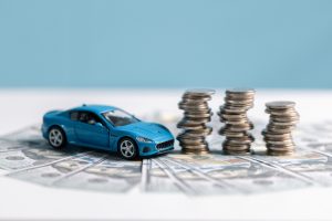 Ein Auto steht neben drei aufgebauten Türmen aus Geldmünzen