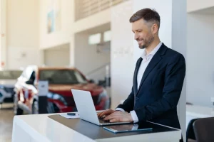 Autoverkäufer arbeitet am Laptop an einem Schreibtisch im Autohaus