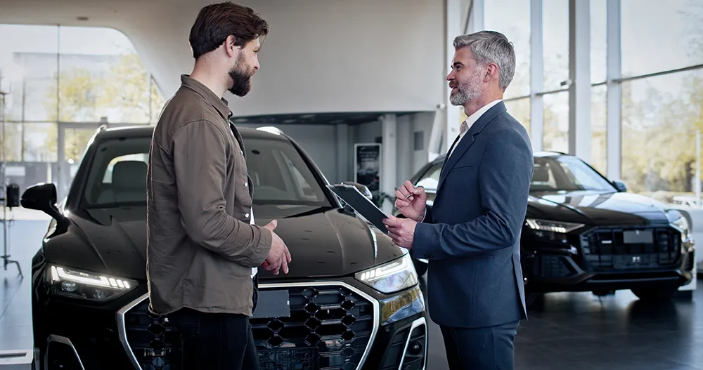 Beratungsgespräch zwischen Autohändler und Kunde im Autohaus