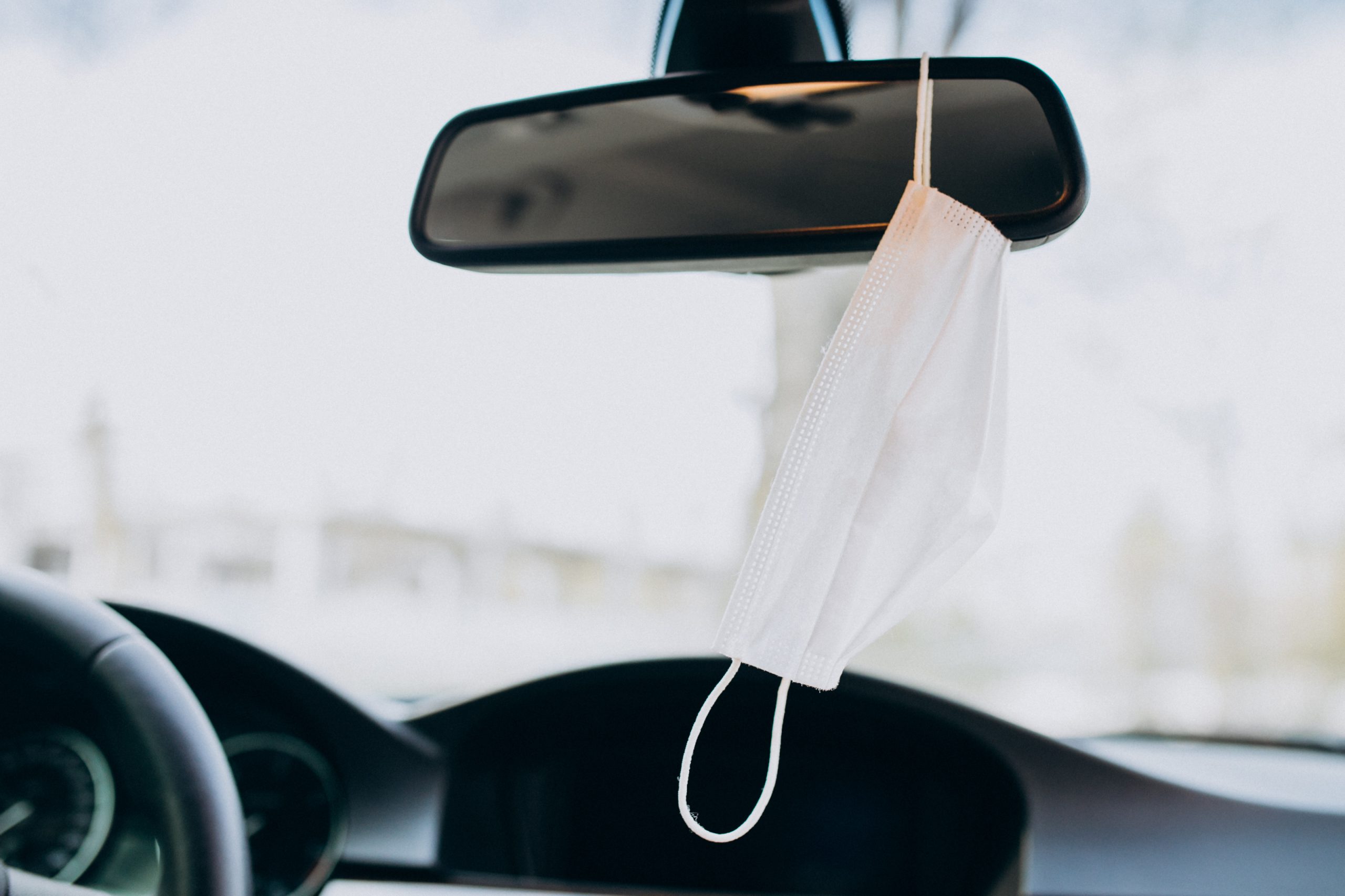 Gesichtsmaske am Rückspiegel im Auto