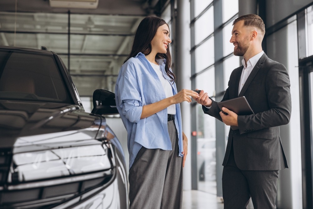 Verkäufer übergibt Schlüssel an glückliche Kundin