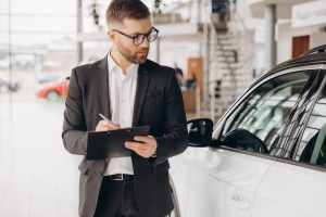 Mitarbeiter im Anzug überprüft Autos im Autohaus